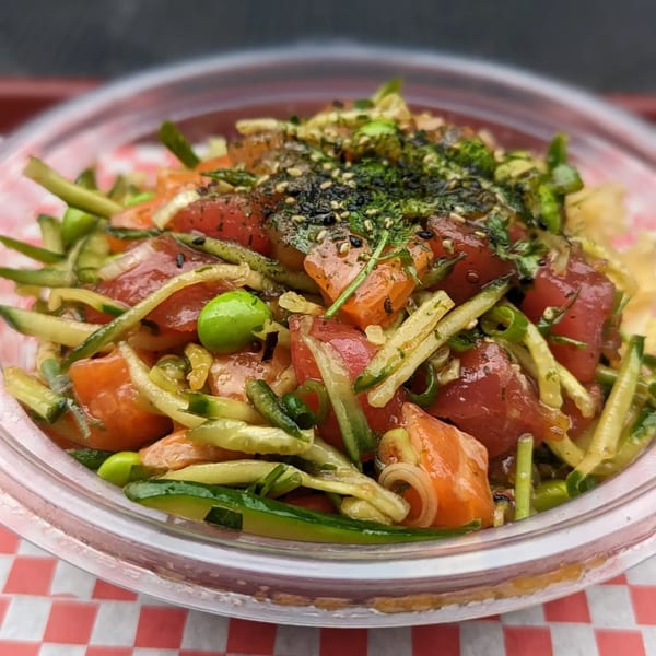 A vibrant poke bowl from Poke Pub, featuring fresh tuna, salmon, cucumber, and edamame.